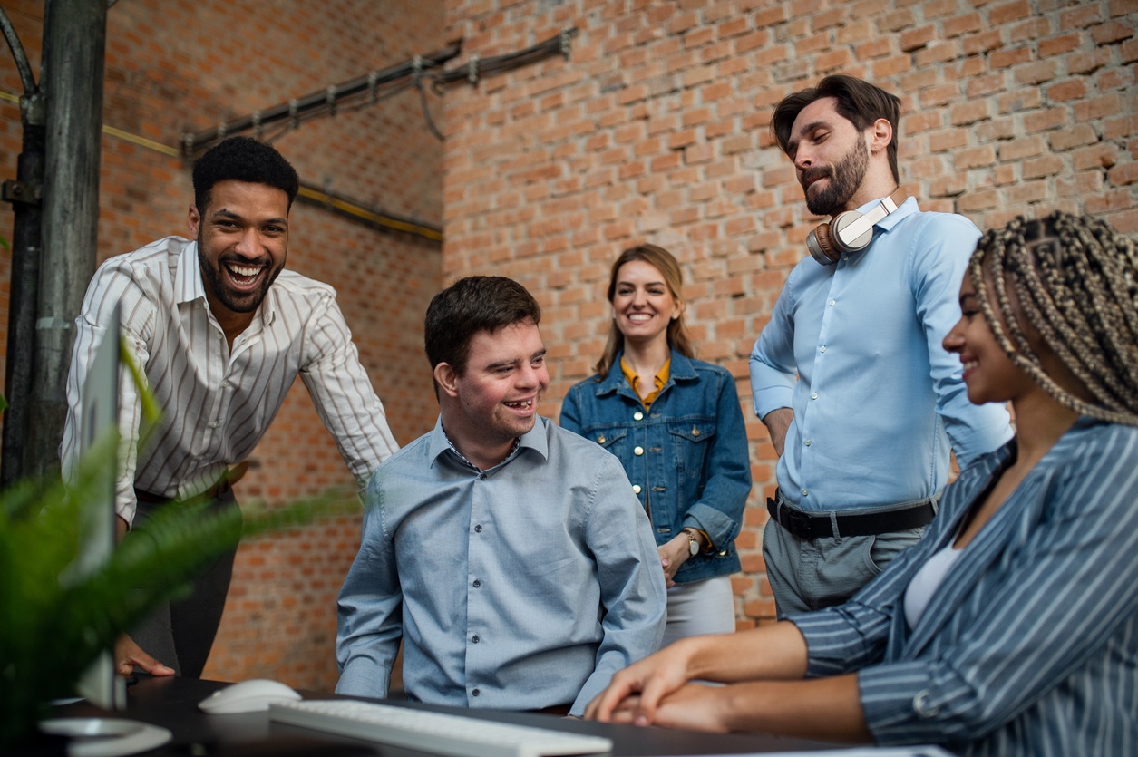 Happy down syndrome man with business colleagues in office