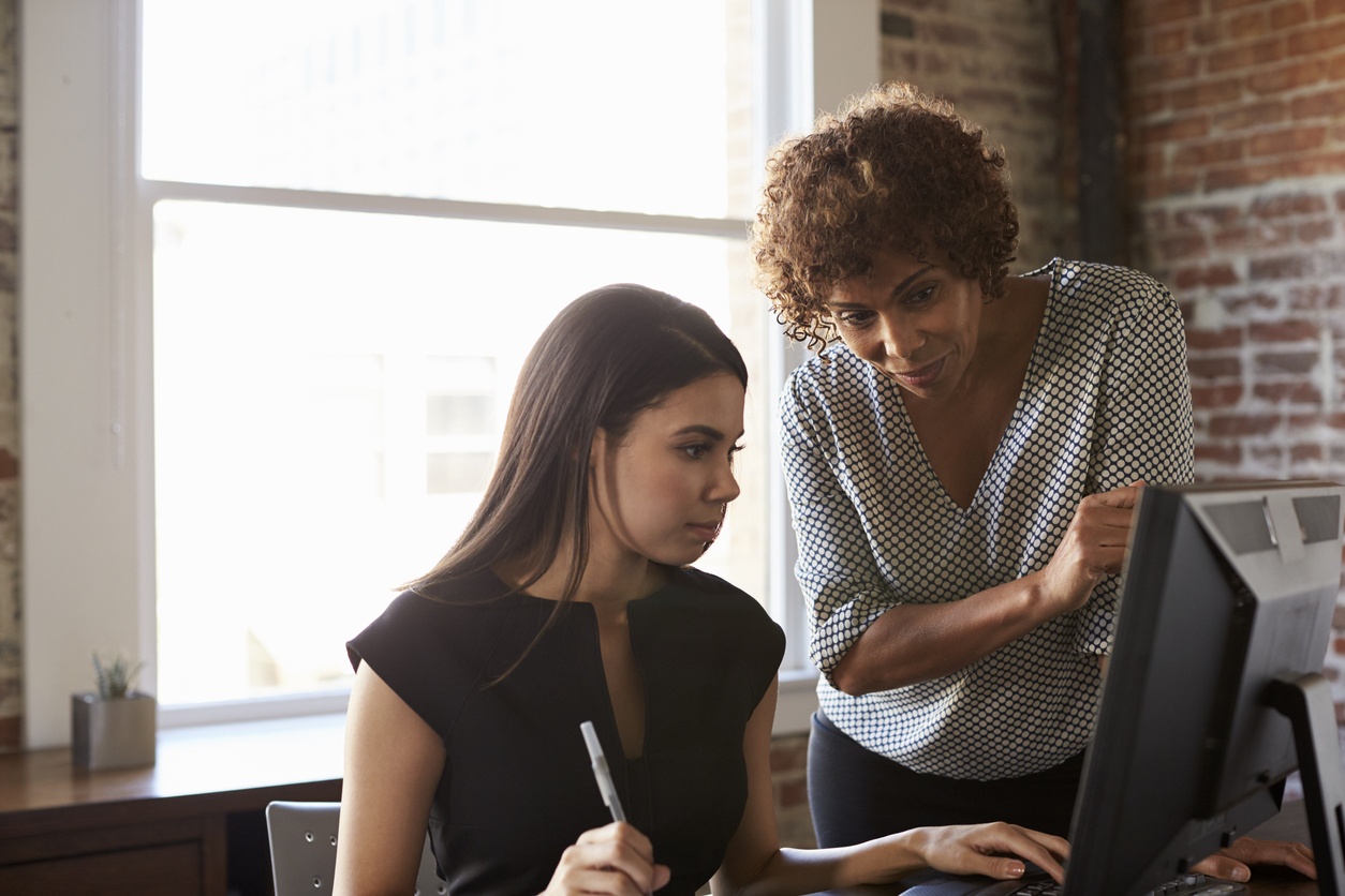 An older woman helping a younger woman on the computer